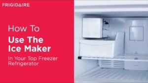 A modern refrigerator freezer filled with fresh ice cubes in a bright kitchen.