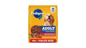 A happy dog sitting beside a bowl of complete dog food in a modern kitchen.