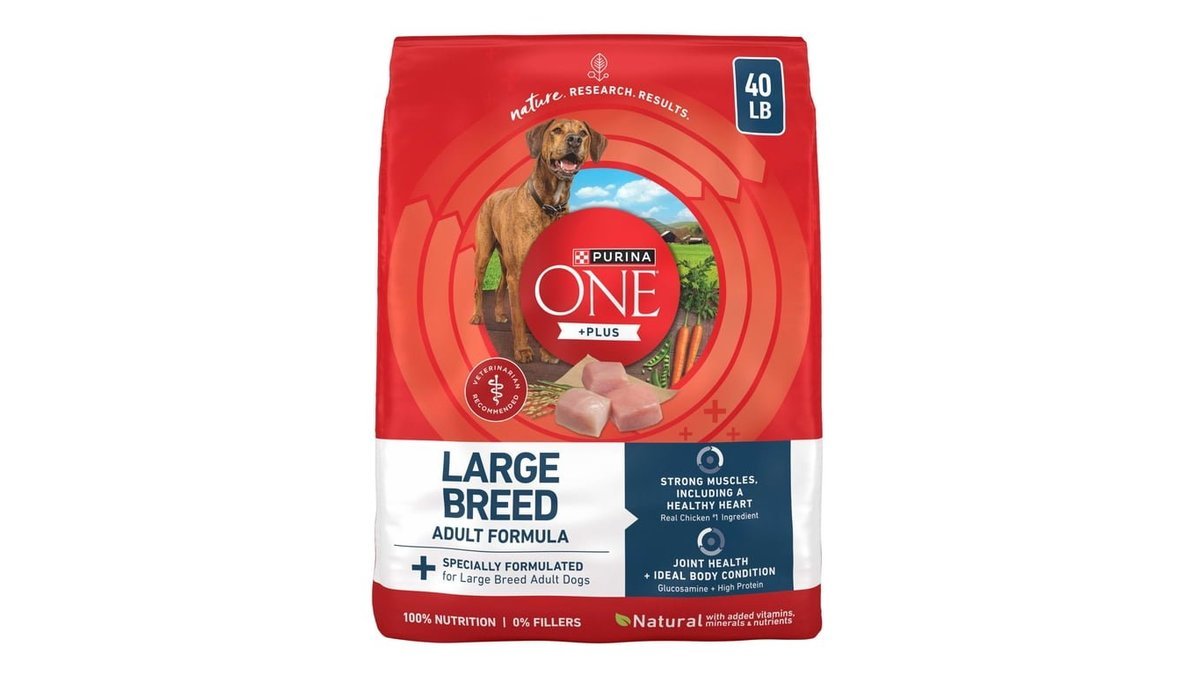 A large bag of dog food sits beside a metal bowl.