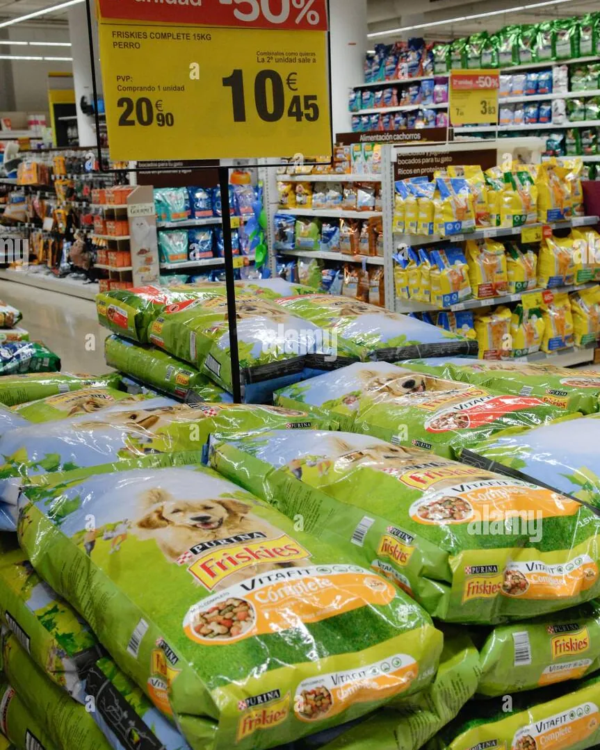Large bag of dog food sitting on a wooden floor near a bowl.